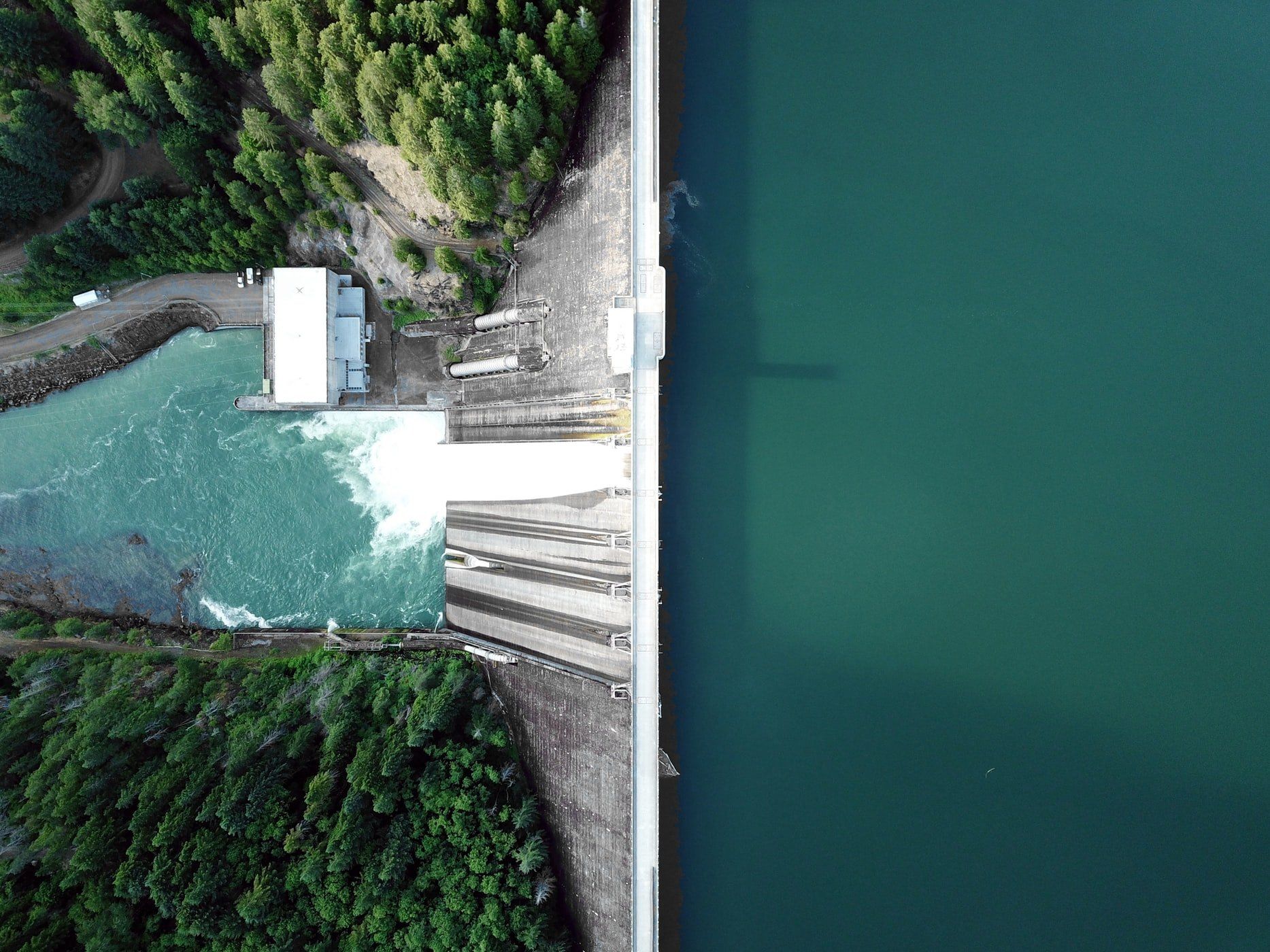 An aerial view of a dam surrounded by trees and water.