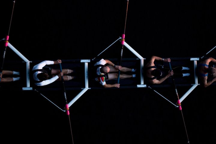 A group of people are rowing a boat in the dark.