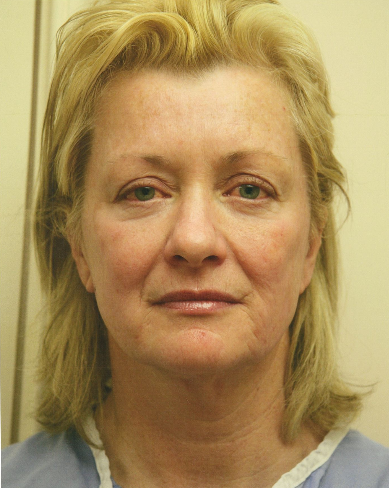 Woman with blonde hair, looking directly at the viewer. She has fair skin and is wearing a blue top.