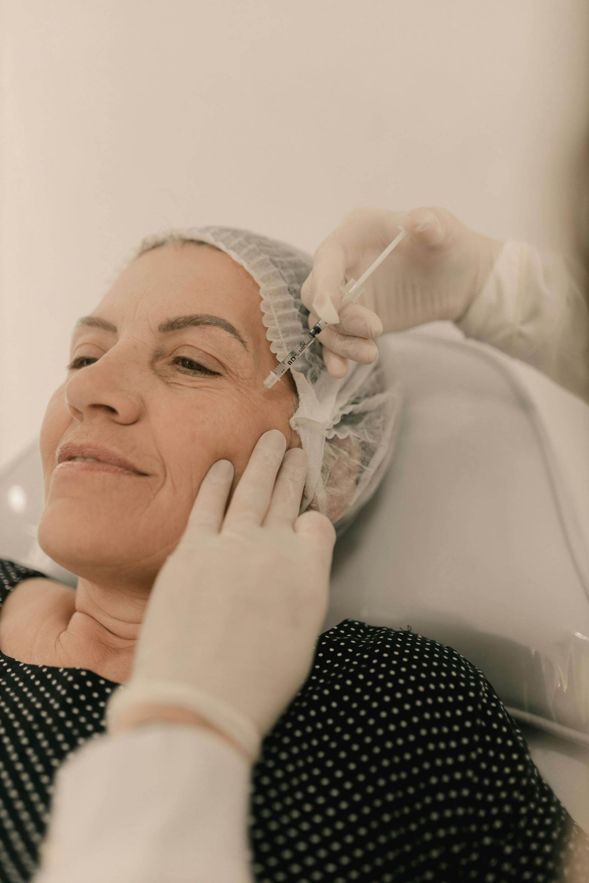 Woman receiving facial injection from a person in a medical setting.