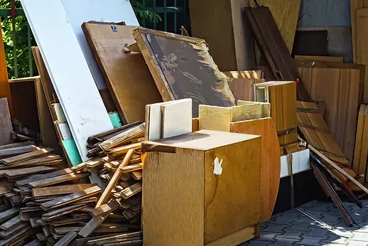 Pile of discarded wooden furniture and boards outdoors.