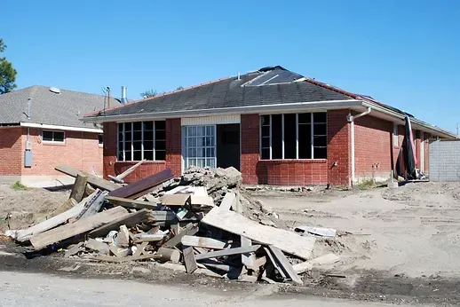Brick building with broken windows and debris in front.