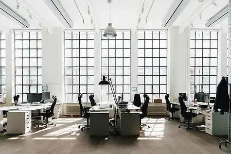 An empty office with lots of windows and desks and chairs.