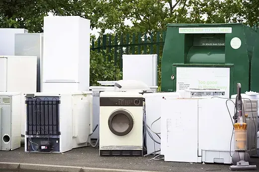 A bunch of white appliances are sitting on the side of the road.