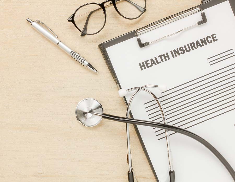 Health insurance form with stethoscope, pen, and eyeglasses on a desk