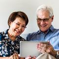Smiling couple looking at a tablet together on a couch