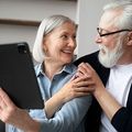 Smiling couple looking at a tablet together on a couch
