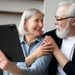 Smiling couple looking at a tablet together on a couch