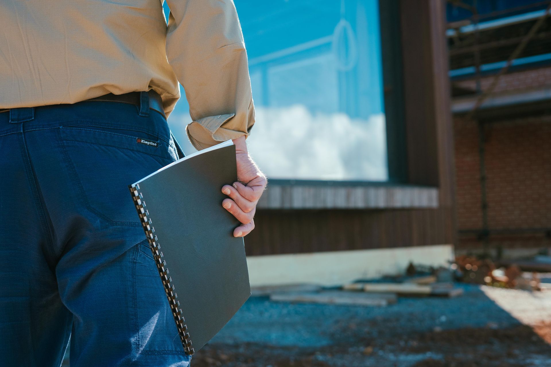 A Person Holding A Black Book On A Site — Focus Building Certifiers In Bowral, NSW