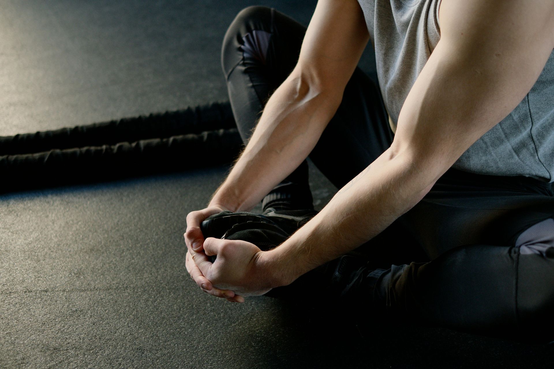A man is sitting on the floor tying his shoes