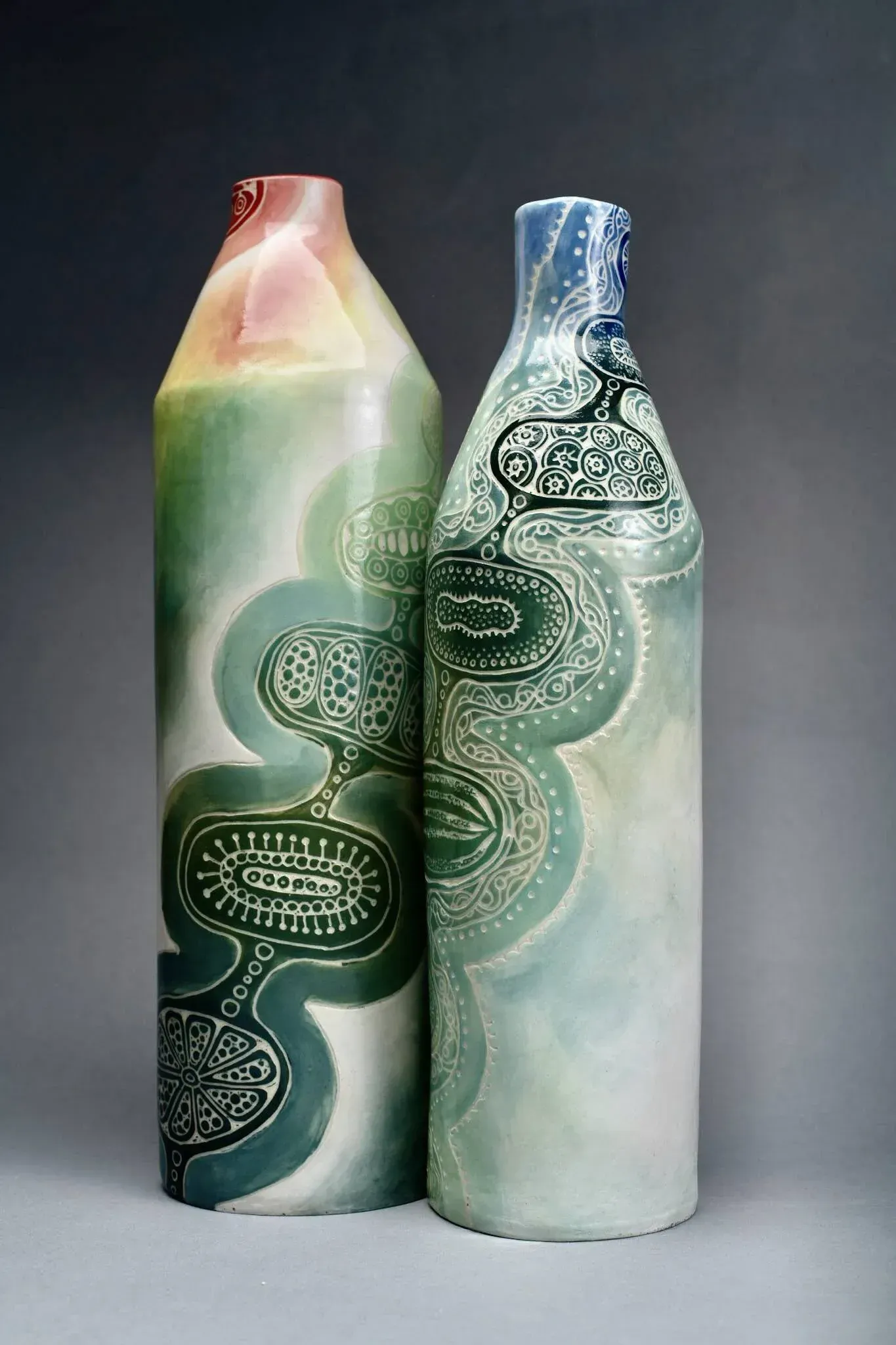 Two bottles decorated in greens and blues with carved detail that represents changes over time