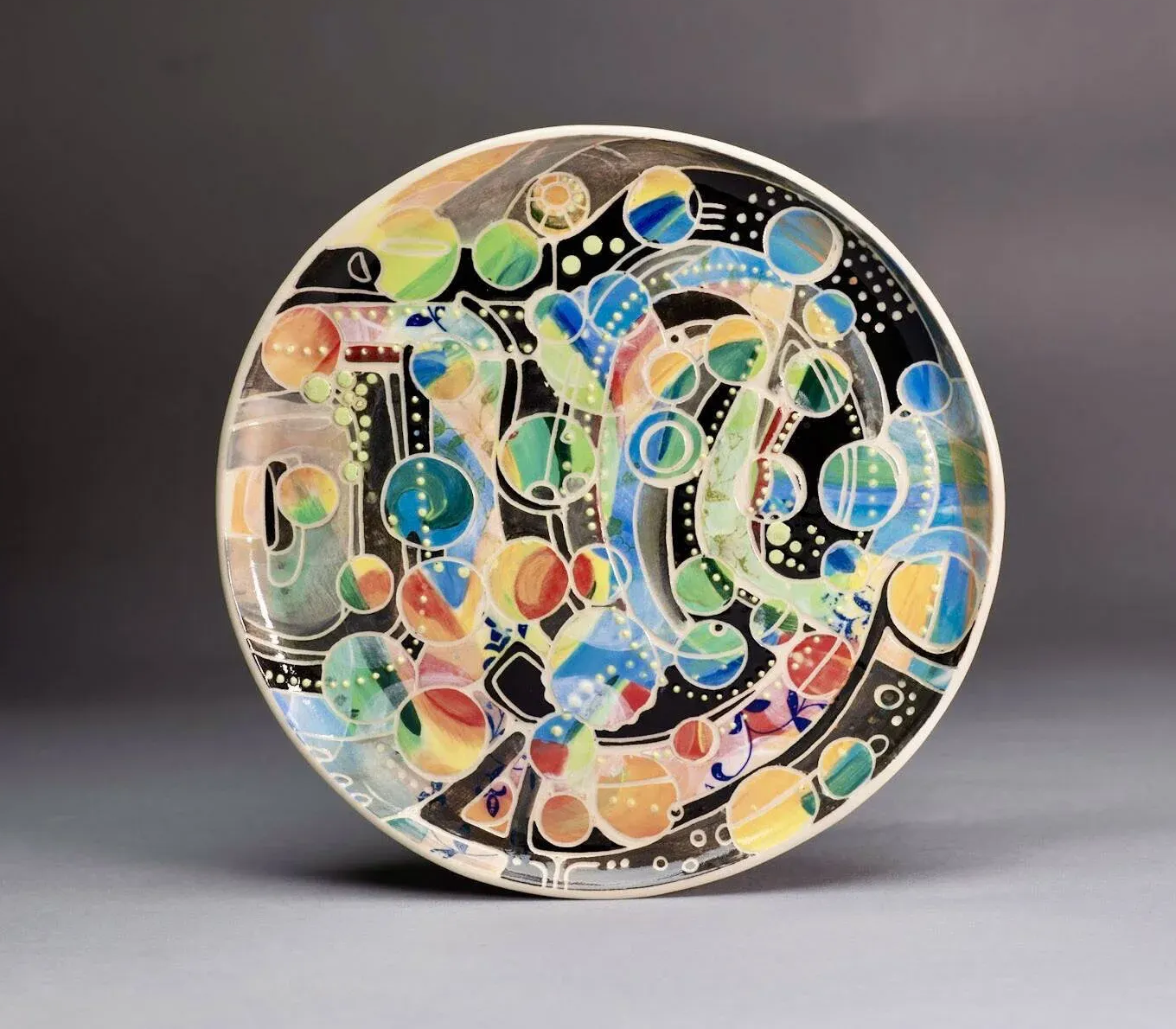 A bright rainbow coloured plate featuring bubbles and the word Joy hidden in the pattern.