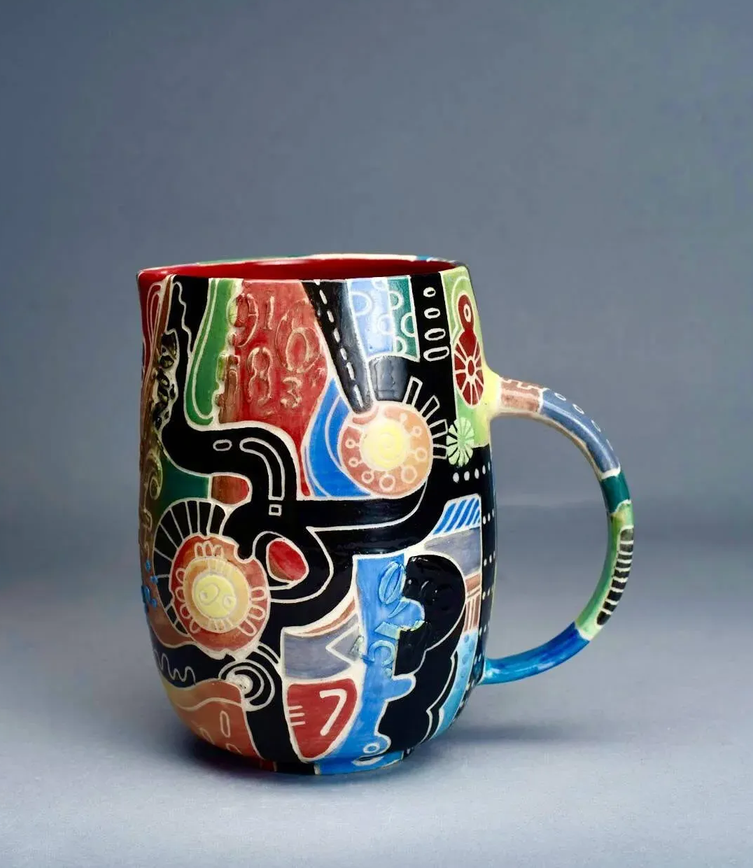 Colorful, patterned ceramic jug; dark red, black, yellow, and blue designs.
