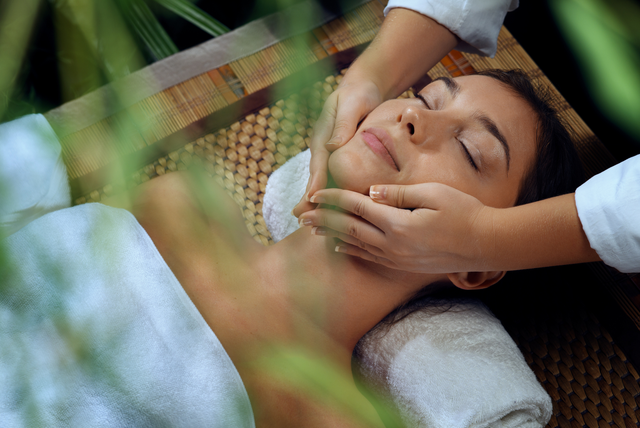 A woman is getting a facial massage at a spa.