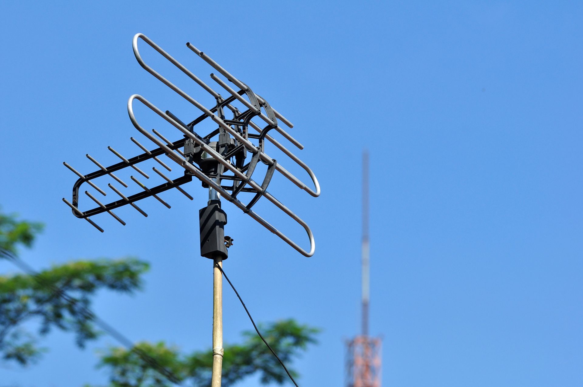Un'antenna è posizionata in cima a un palo di legno contro un cielo azzurro.