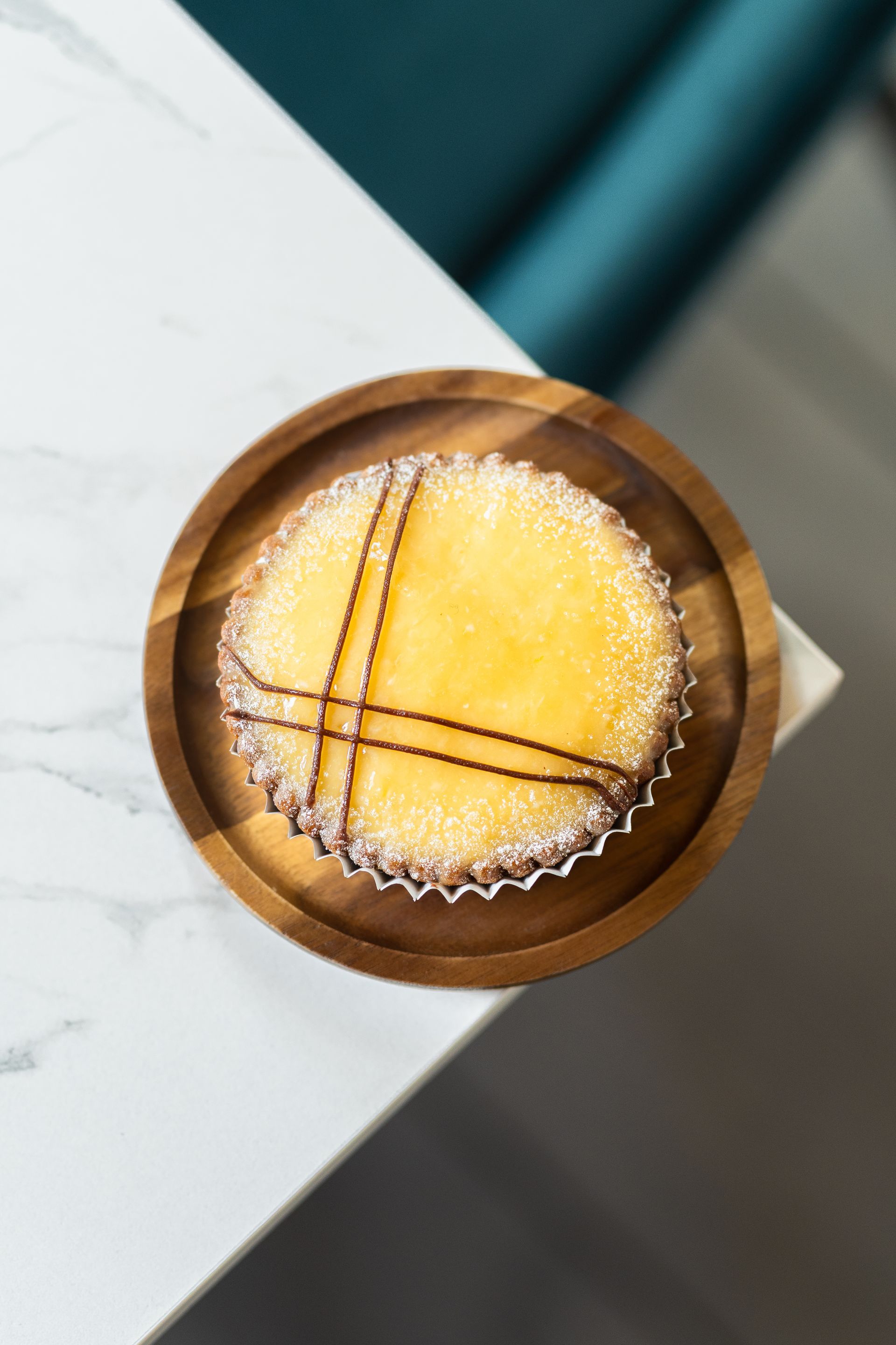 Petit pain rond dans un bol en bois sur une table blanche avec un fond bleu sarcelle flou.