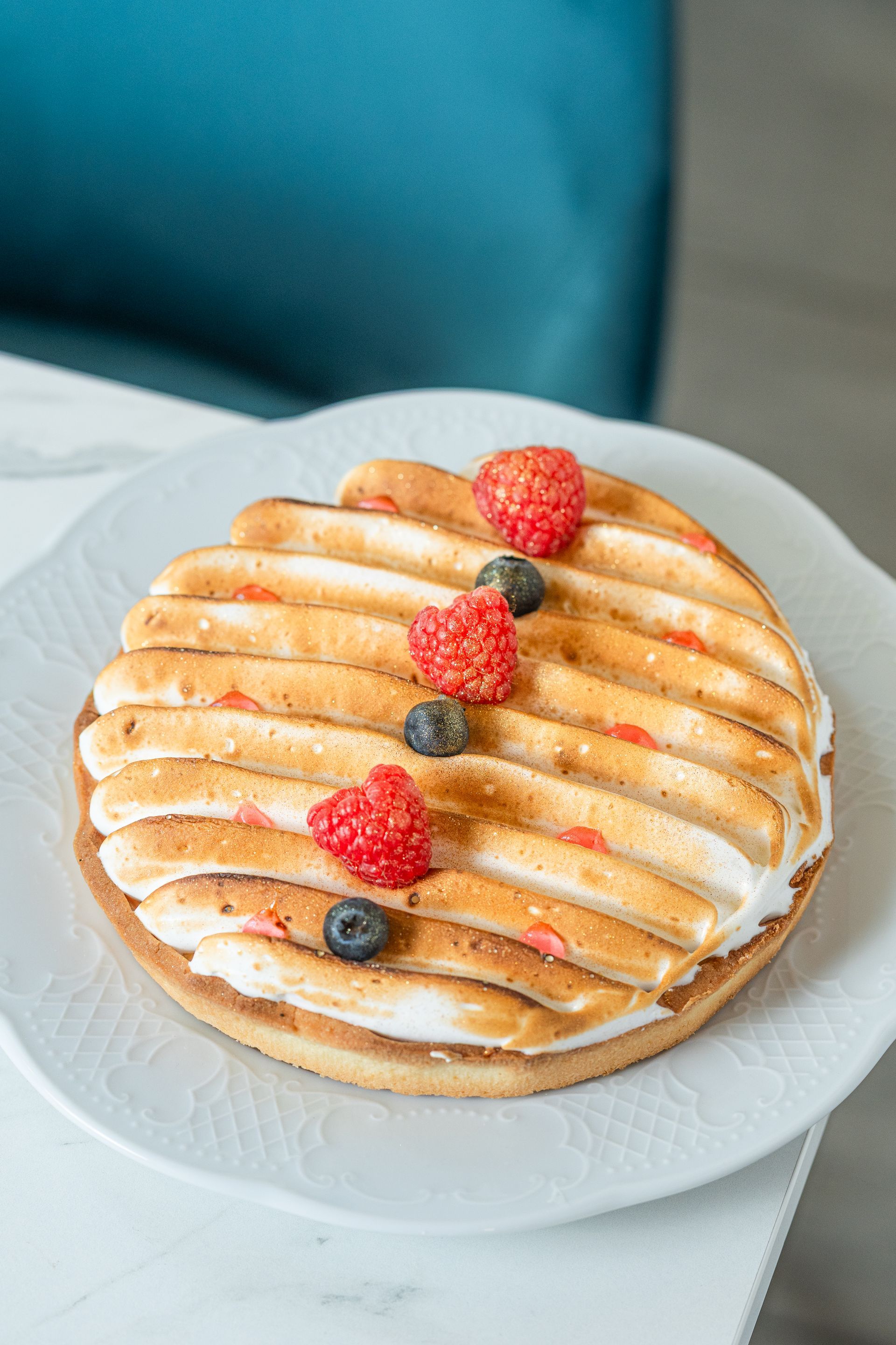 Pâtisserie ronde garnie de fraises et de myrtilles sur une assiette blanche
