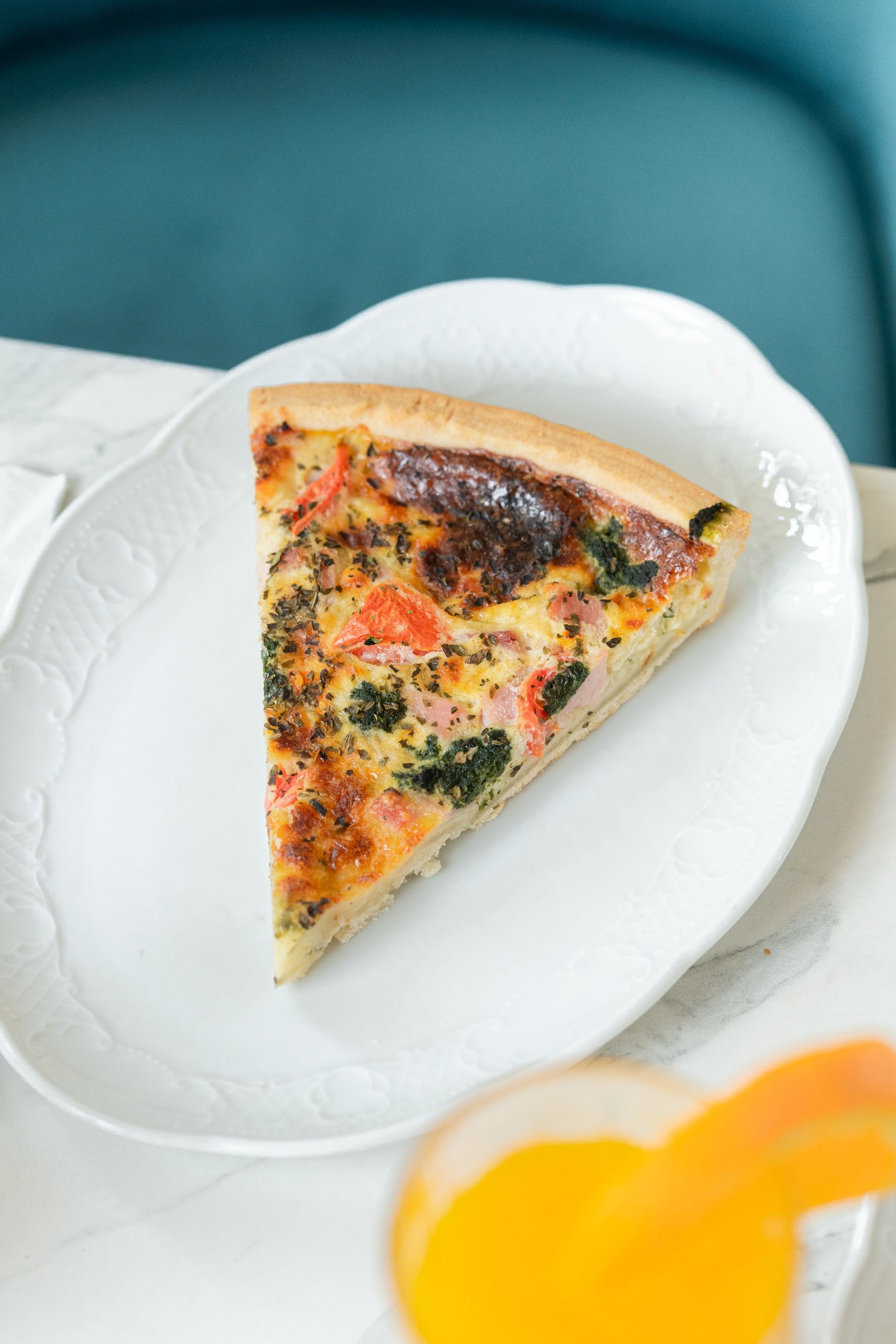 Part de pizza aux légumes sur une assiette blanche avec un fond turquoise