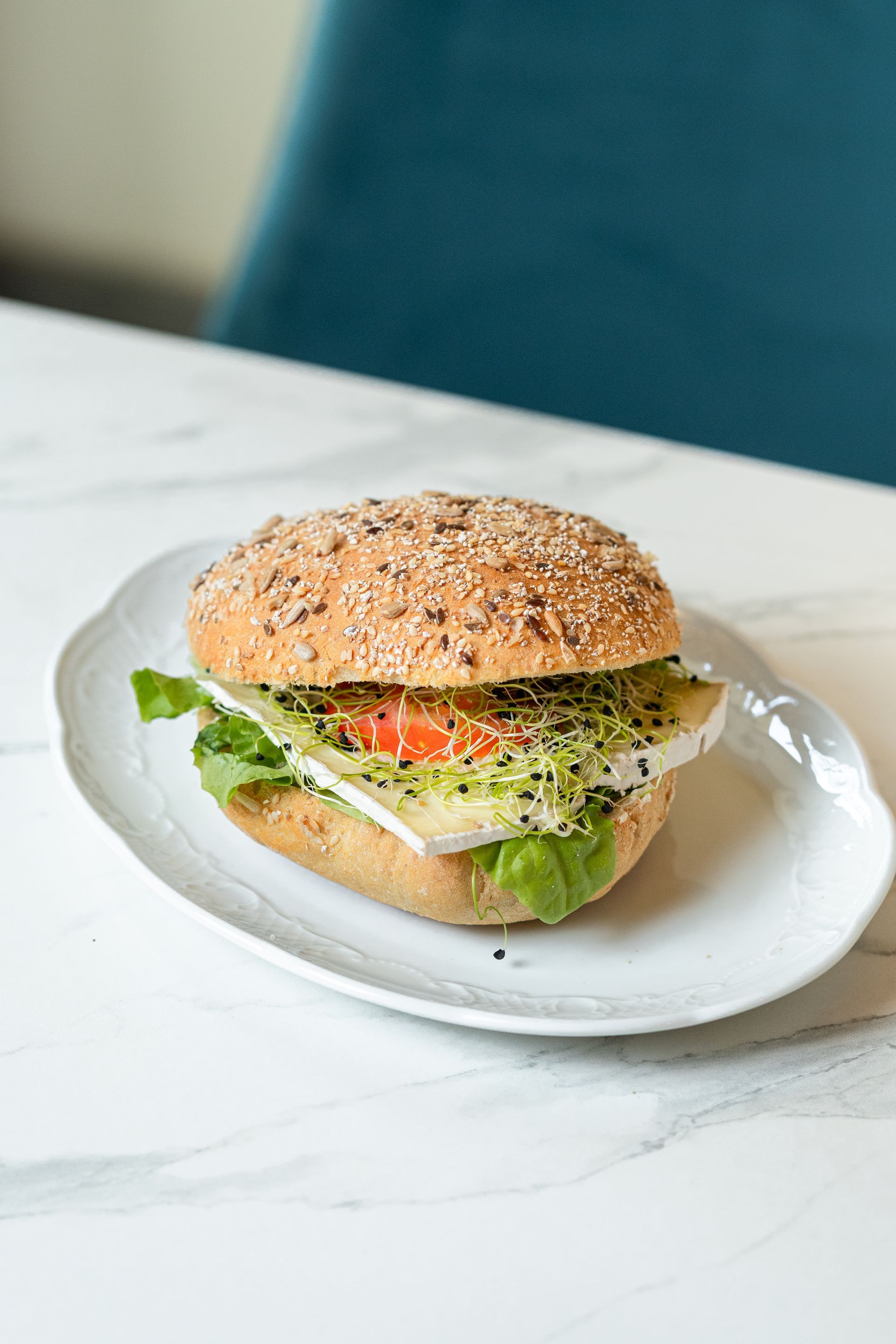 Sandwich multigrains avec laitue et tomate sur une assiette blanche, sur une table