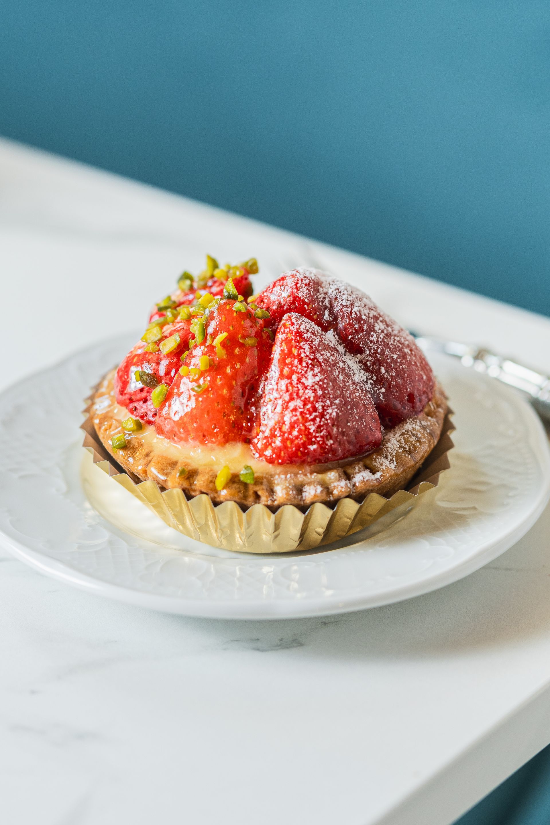 Tarte aux fraises saupoudrée de sucre glace sur une assiette blanche