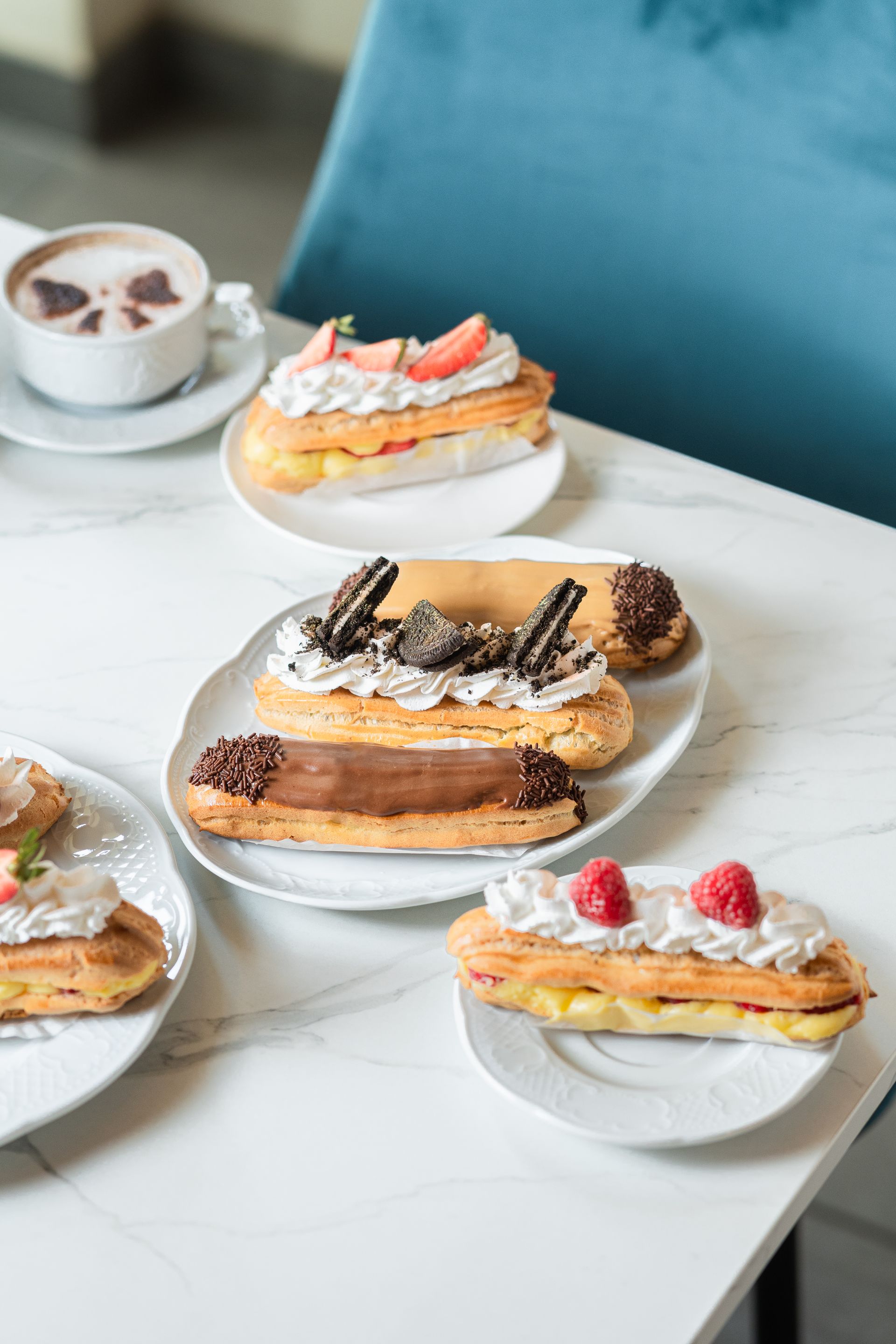 Assortiment de viennoiseries sur des assiettes blanches, accompagné de café, sur une table en marbre dans un café.