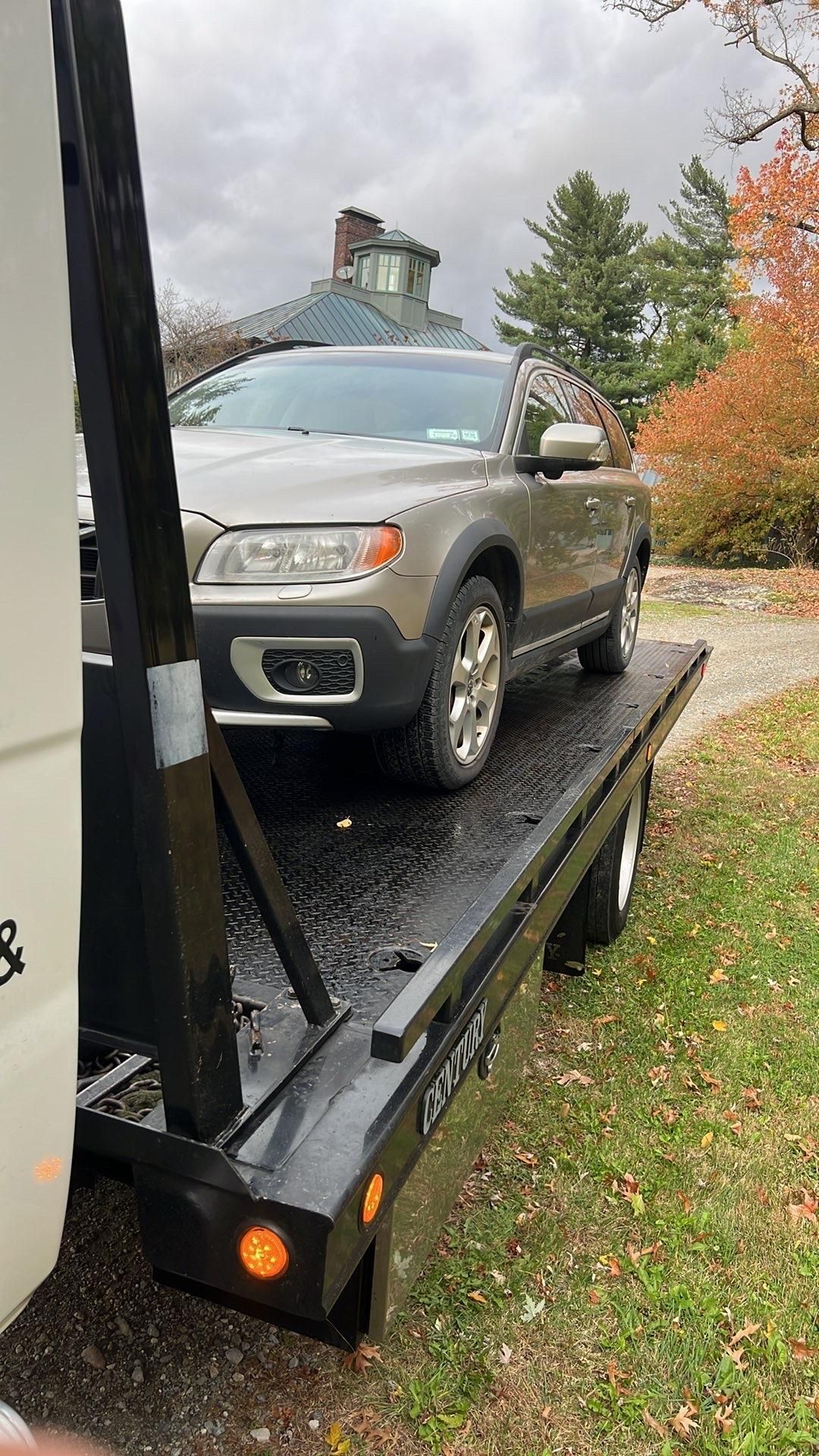 Red car being towed on a city street by a tow truck with flashing lights. Red car being towed on a city street by a tow truck with flashing lights.