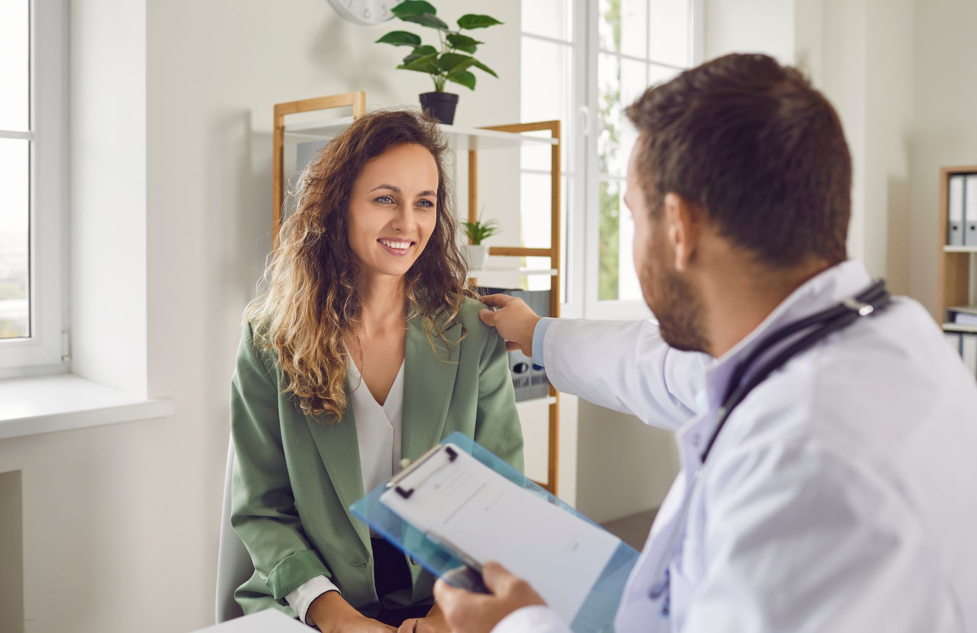 A smiling doctor in a lab coat with a stethoscope around his neck.