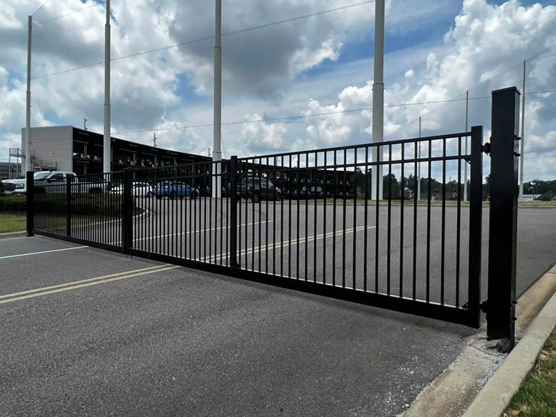 Black metal gate across an empty asphalt lot under a cloudy sky