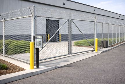 Chain-link security gate with keypad at an industrial building entrance