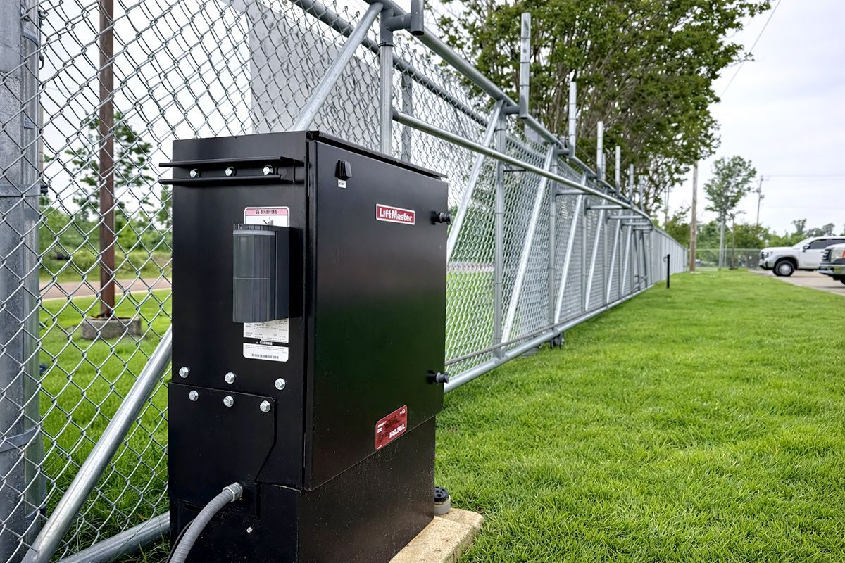 Black utility box beside chain-link fence on a grassy field