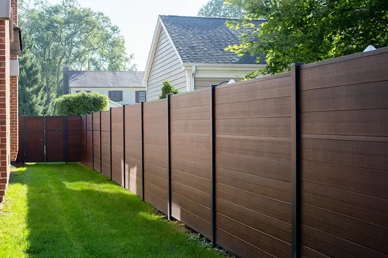 Long brown privacy fence beside a green lawn in a suburban backyard