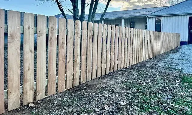 New wooden privacy fence along a snowy backyard beside a house