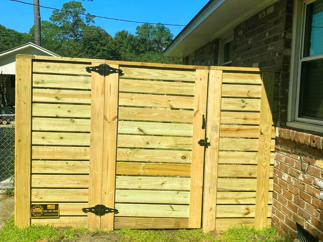Wooden outdoor gate and fence beside a brick house on a sunny day