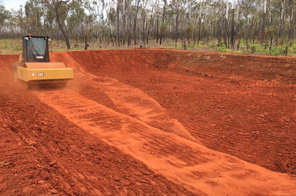 A Bulldozer Is Driving Down A Dirt Road For Site Preparation — Coleman's Contracting & Earthmoving In Katherine, NT