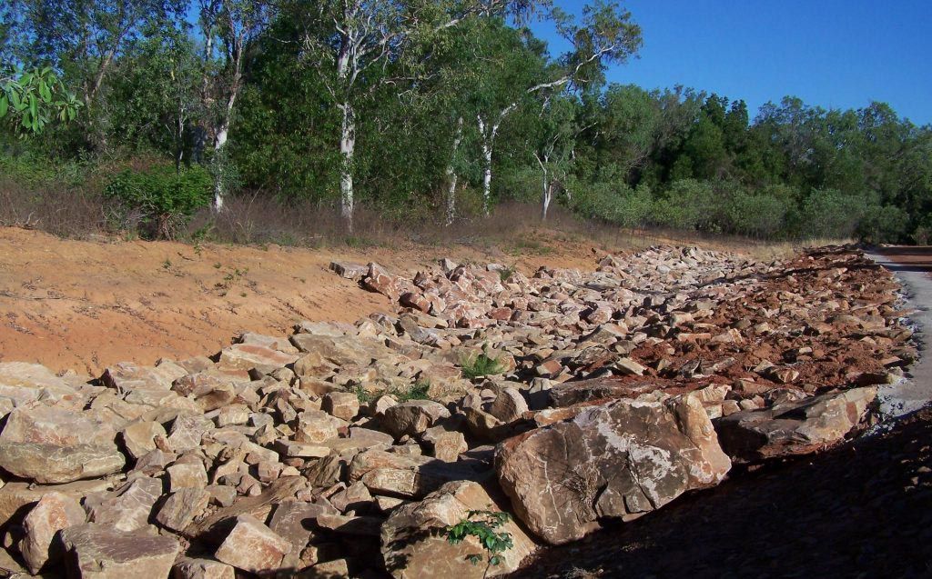 A Pile Of Rocks In A Field With Trees In The Background — Coleman's Contracting & Earthmoving In Katherine, NT