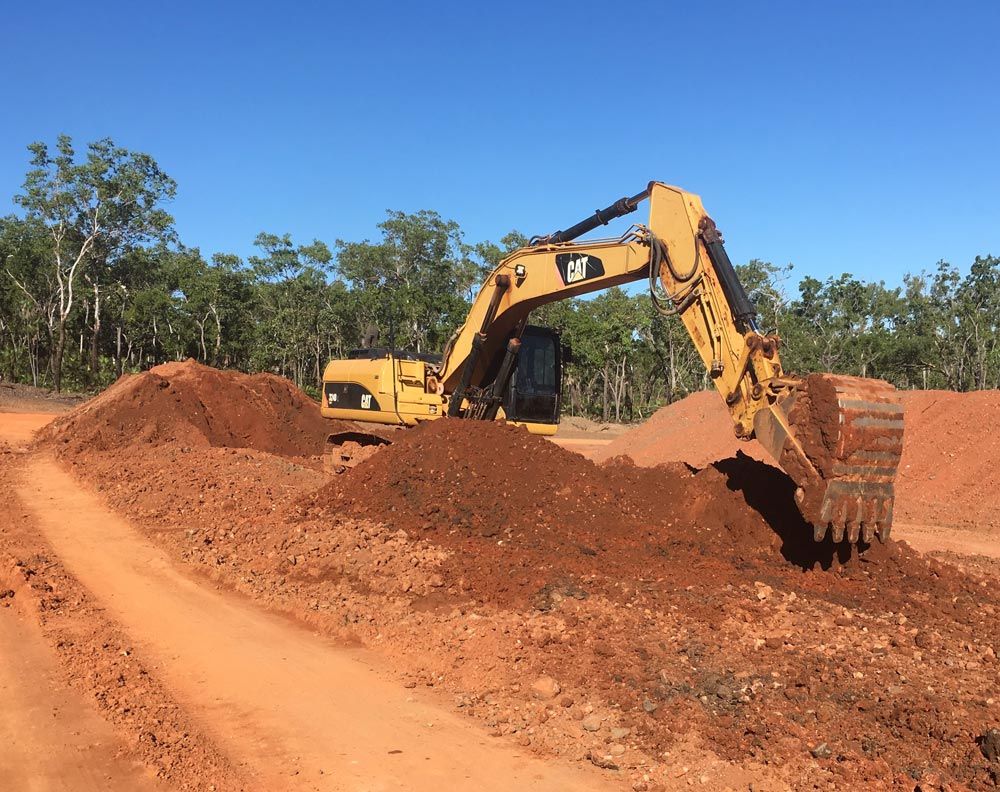 Yellow Excavator Is Collecting A Dirt In Piles On Dirt Field — Coleman's Contracting & Earthmoving In Humpty Doo, NT