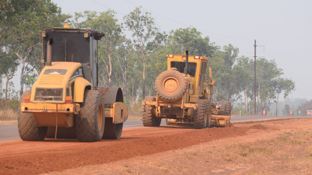 Two Yellow Tractors Are Driving Down A Dirt Road — Coleman's Contracting & Earthmoving In Humpty Doo, NT