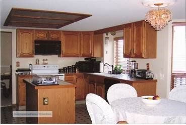 A kitchen featuring wooden cabinets, a central island, a white stove, and a dining table with chairs under a chandelier.