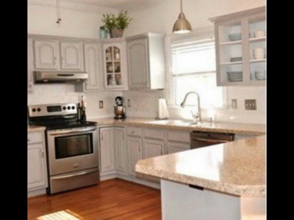 A bright kitchen with light grey cabinets, stainless steel appliances, granite countertops, and hardwood floors.