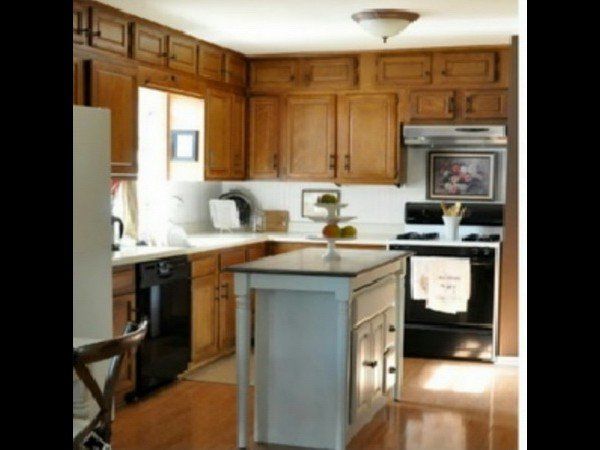 A kitchen featuring wood cabinets, a light-colored central island, black appliances, and white countertops.