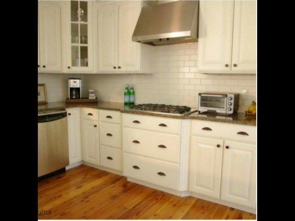A bright kitchen featuring white cabinets, stainless steel appliances, a subway tile backsplash, and light wood floors.