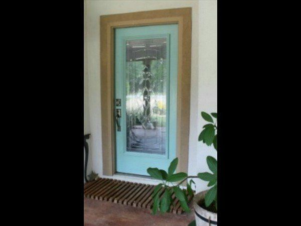 A light blue front door with a large vertical glass panel, framed in wood, situated at an entryway with a slatted mat.