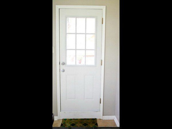 A white, rectangular door with a nine-pane window at the top, installed in a beige interior wall.