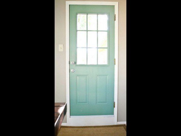 A light teal exterior door with a nine-pane window at the top, set within a white frame against a grey wall.