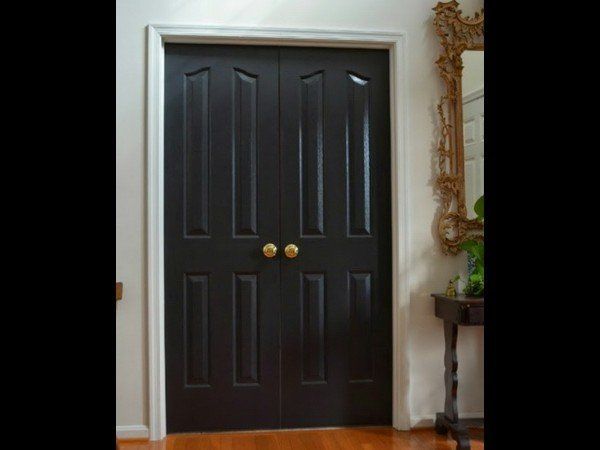 A set of dark brown, double-panel interior doors with brass knobs, set within a white frame against a white wall.