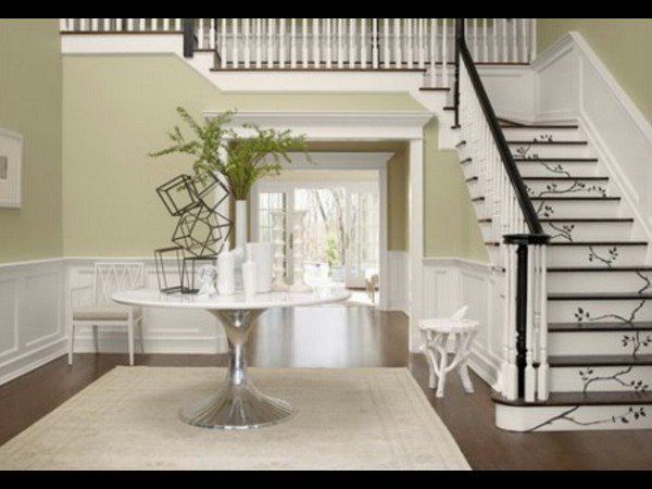 A grand entryway features sage green walls, white wainscoting,