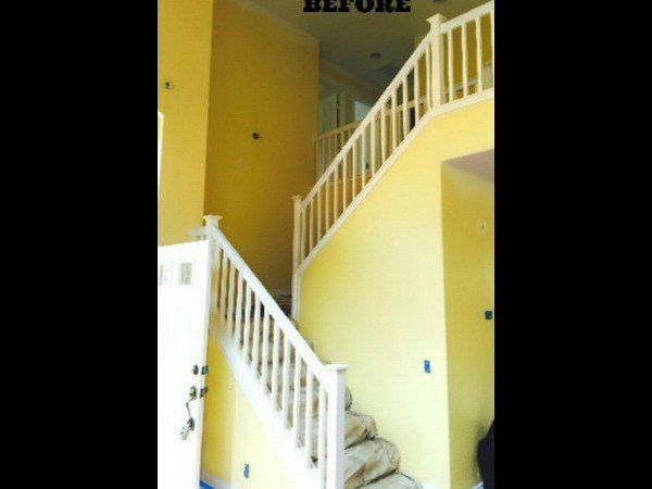 A staircase with white railings in an entry hall with bright yellow walls. The word 