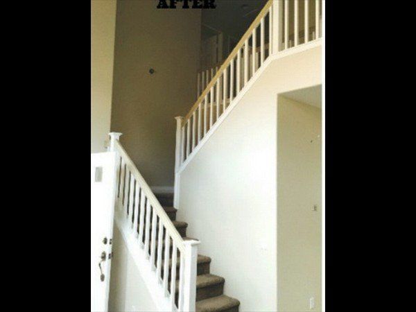A staircase with white railings ascends along a light-colored wall in a bright, modern foyer.