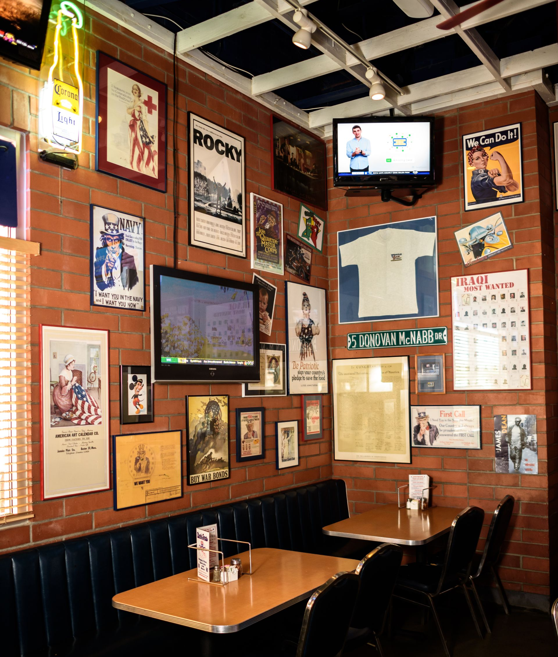 Cozy restaurant booth with framed posters, exposed beams, and a small TV on a wood-paneled wall
