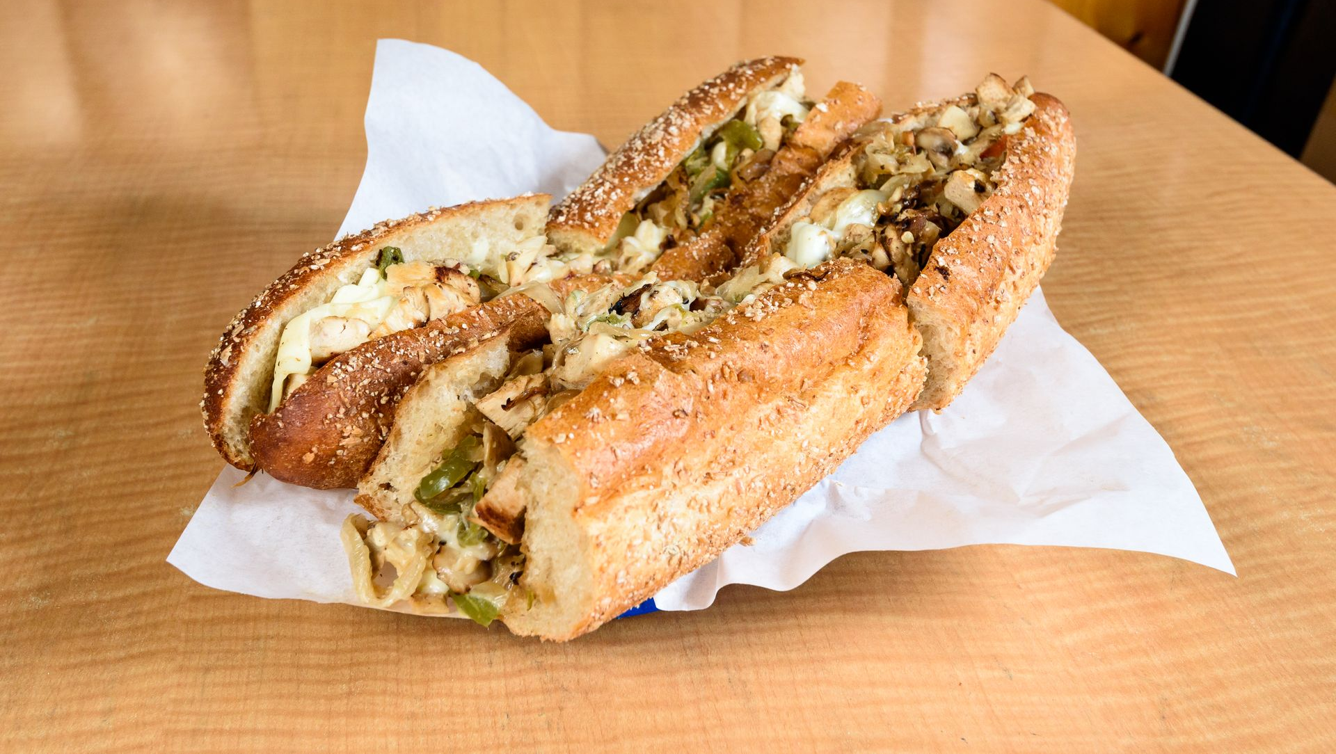Garlic bread slices on white paper in a wooden booth, topped with herbs and melted cheese